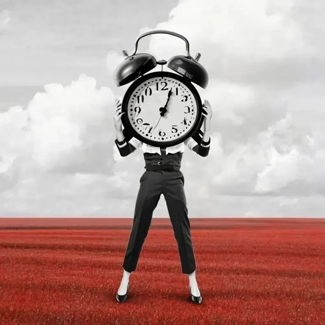 Man holding an alarm clock in a field, symbolizing effective time management strategies.