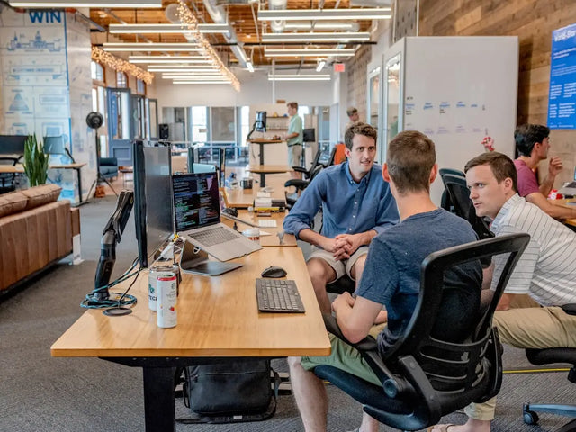 Group of team members collaborating at a shared desk, embodying mindful leadership.