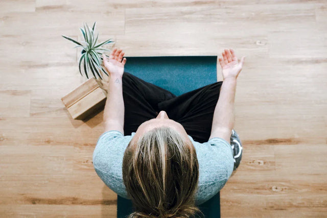 Person practicing mindfulness techniques in butterfly yoga pose on teal mat for mental clarity