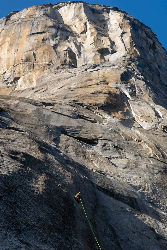 Lone climber ascending granite rock face symbolizing personal growth with Avodah Dynamics stylish motivational clothing