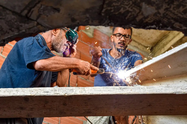 Two people engaging in physical activity while welding metal, enhancing workplace culture.