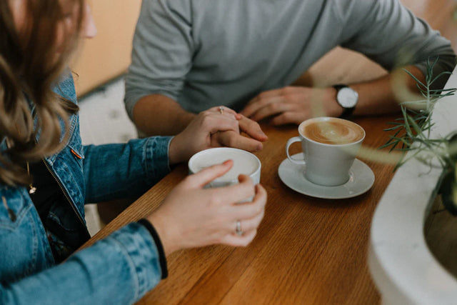 Two coffee cups featuring latte art on a wooden table, symbolizing school leaders’ discourse.