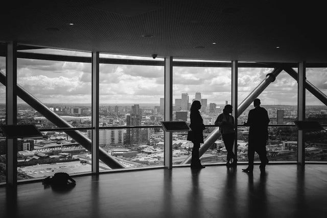 Silhouettes of three people at a window overlooking a cityscape enhancing social media strategies.