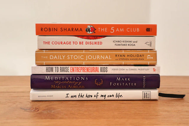 Stack of six self-help and philosophical books inspiring success stories and hustle culture