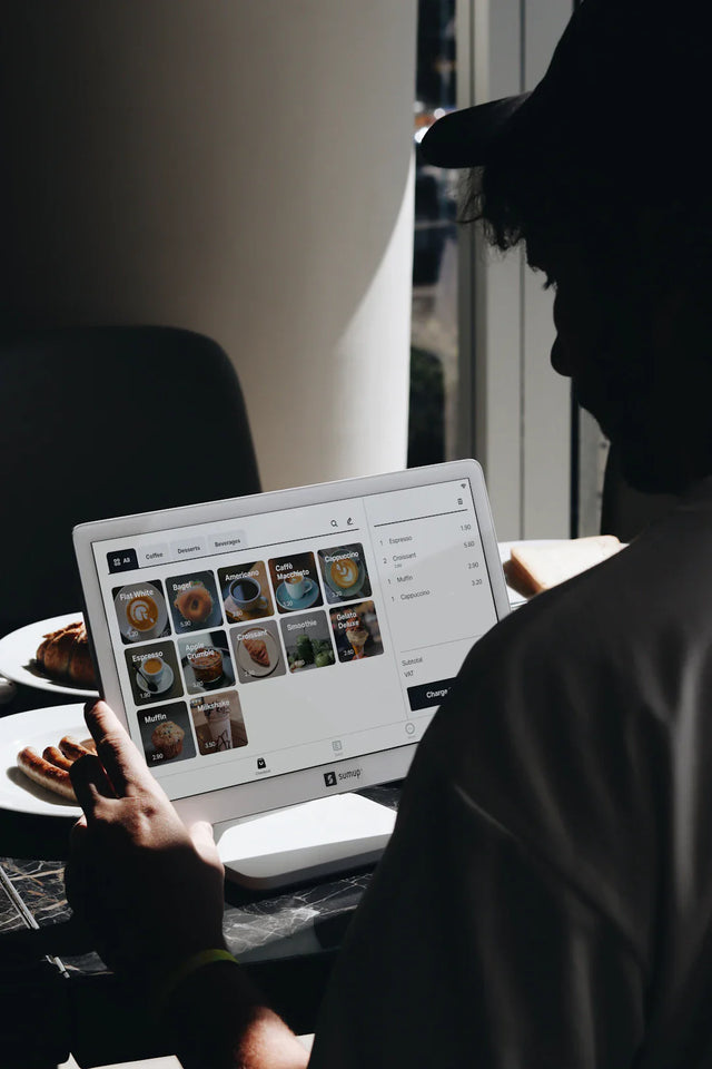 Person using POS tablet showcasing food and drink menu to enhance success techniques in e-commerce businesses