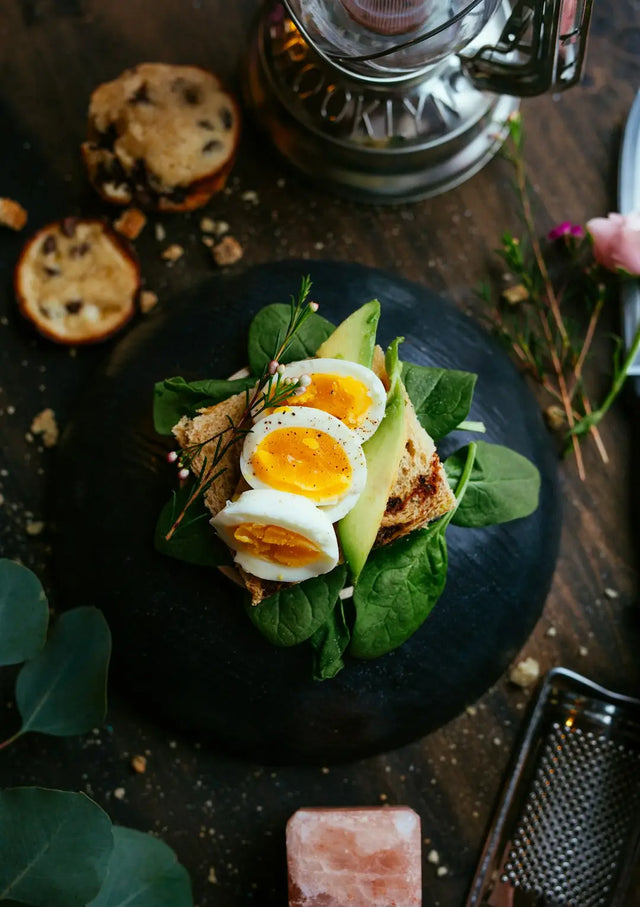 Sliced boiled eggs on avocado and greens, exemplifying mindful eating in hustle culture.