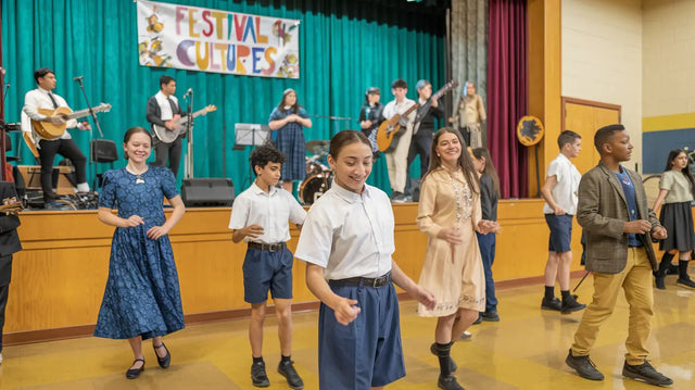 Students performing energetically under a Festival banner, embodying transforming school leadership.