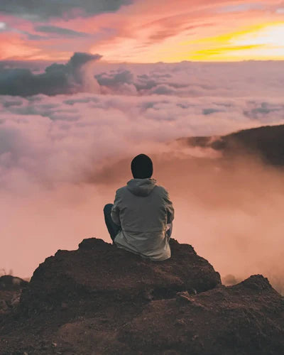 Person sitting alone on a rocky peak symbolizing the shift towards healthy workplace culture.