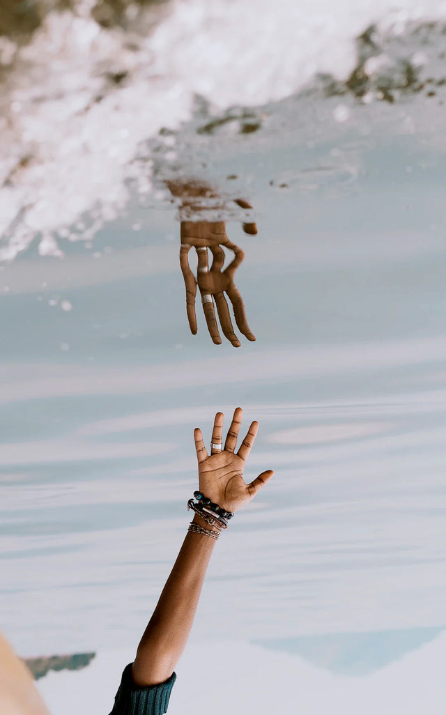 Hands reaching out with reflected water image for personal growth and guided meditation