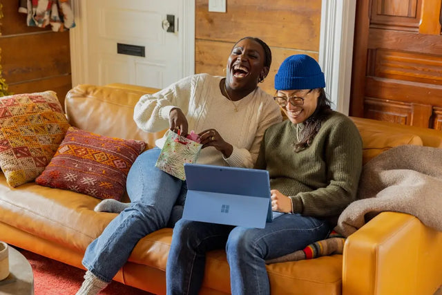 Couple on couch engaging with laptop, embodying hustle culture and personal growth.