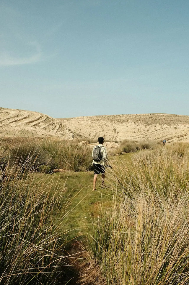 Person walking on grassy trail, promoting physical health and mental wellness.