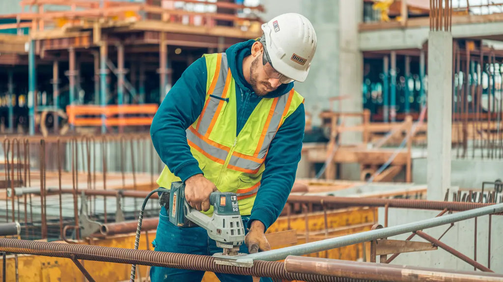 Construction worker in safety gear using a power tool at Avodah Dynamics job site.