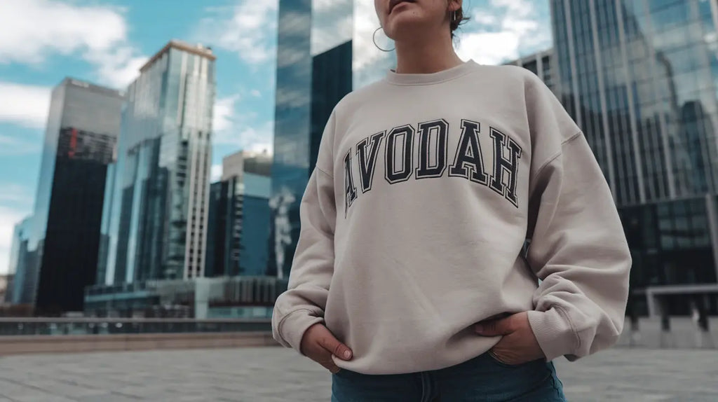 Cream-colored sweatshirt with IVODAH text, embodying hustle culture in a vibrant world.