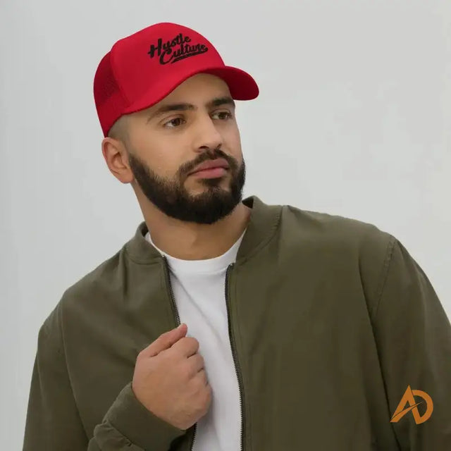 Man showcasing the Classic Hustle Culture Trucker Cap in a red hat and jacket