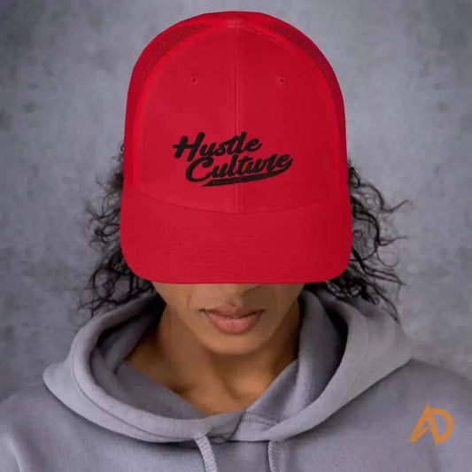 Woman showcasing Classic Hustle Culture Trucker Cap with red hat featuring ’hut’ design