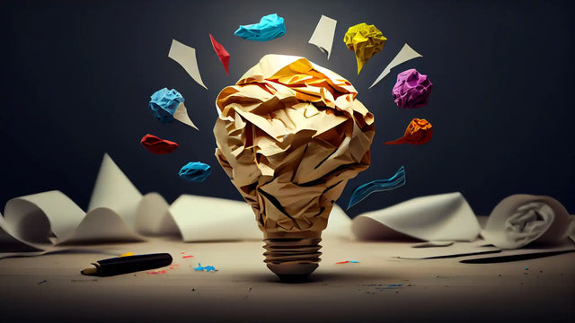 Crumpled brown paper shaped like a light bulb with colorful paper pieces floating around it.