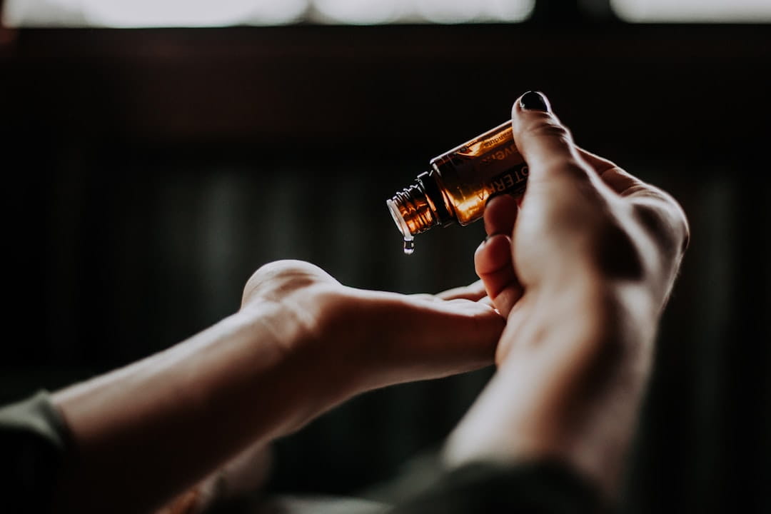Hands dispensing liquid drops from amber bottle for stress management techniques or stress relief tips