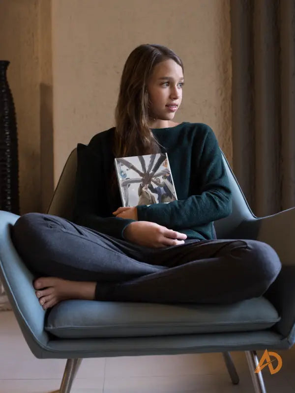 Individual seated cross-legged in a modern chair reading about High-Performing Team dynamics