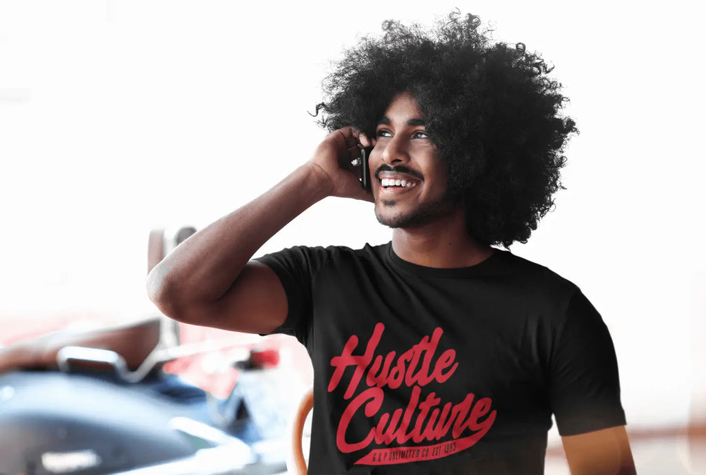 Person in a black Hustle Culture t-shirt with afro hairstyle, embodying hard work ethos.