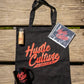 Black bag featuring a Hustle Culture book, a bottle of beer, and color pencils