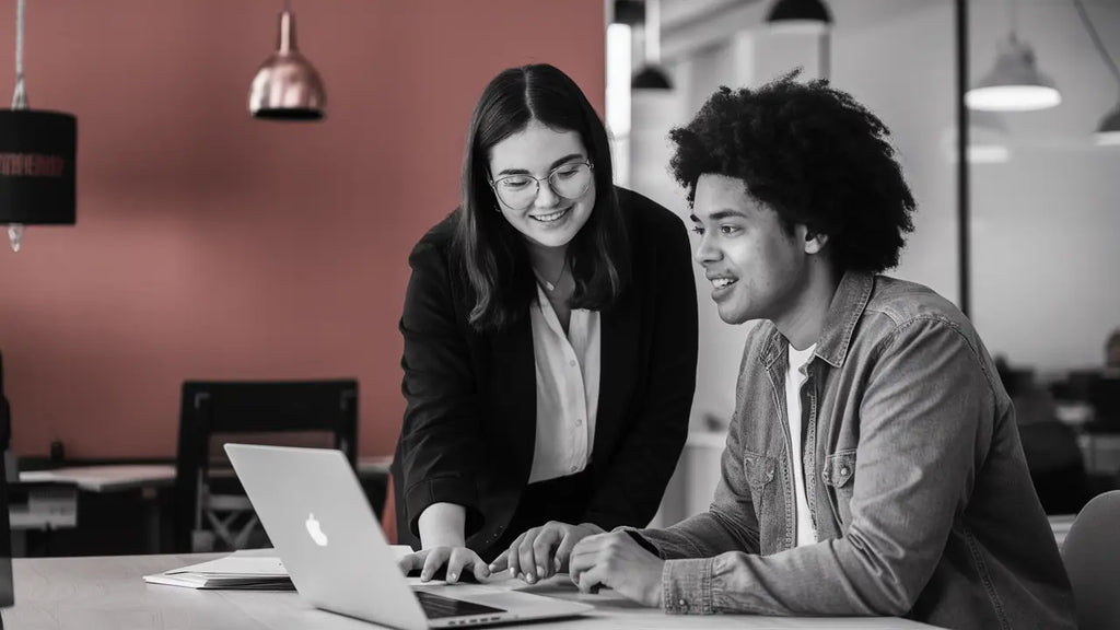 Two coworkers collaborating on a laptop to enhance personalized career success.