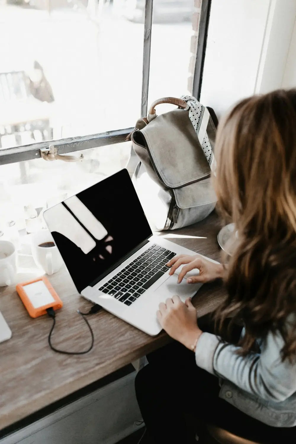 Person using a silver laptop with dark screen demonstrating stress management techniques