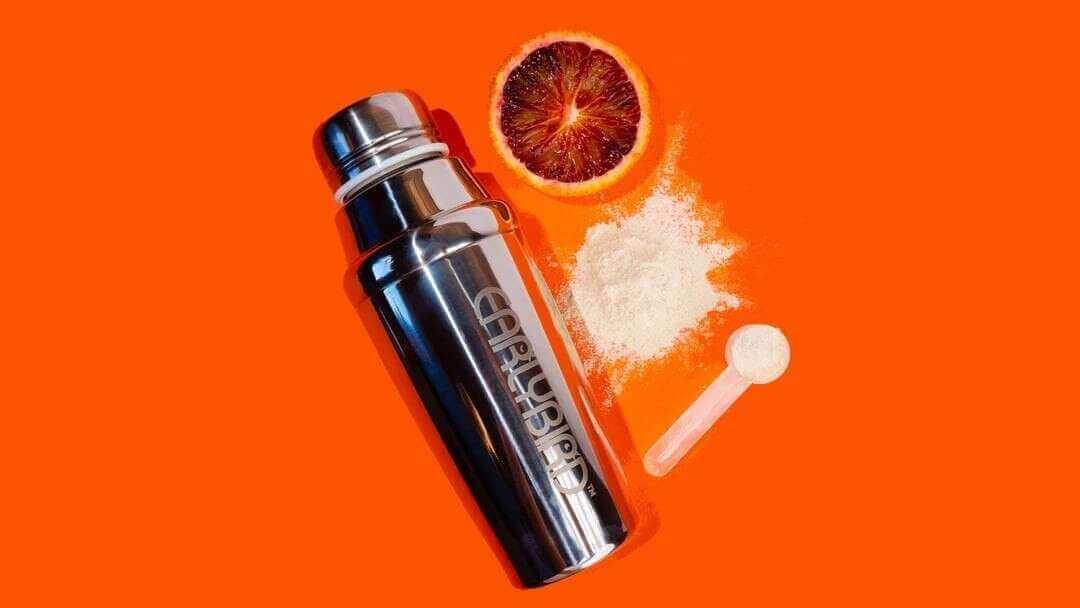 Silver stainless steel shaker bottle with black lid and white powder for perfect morning routine.