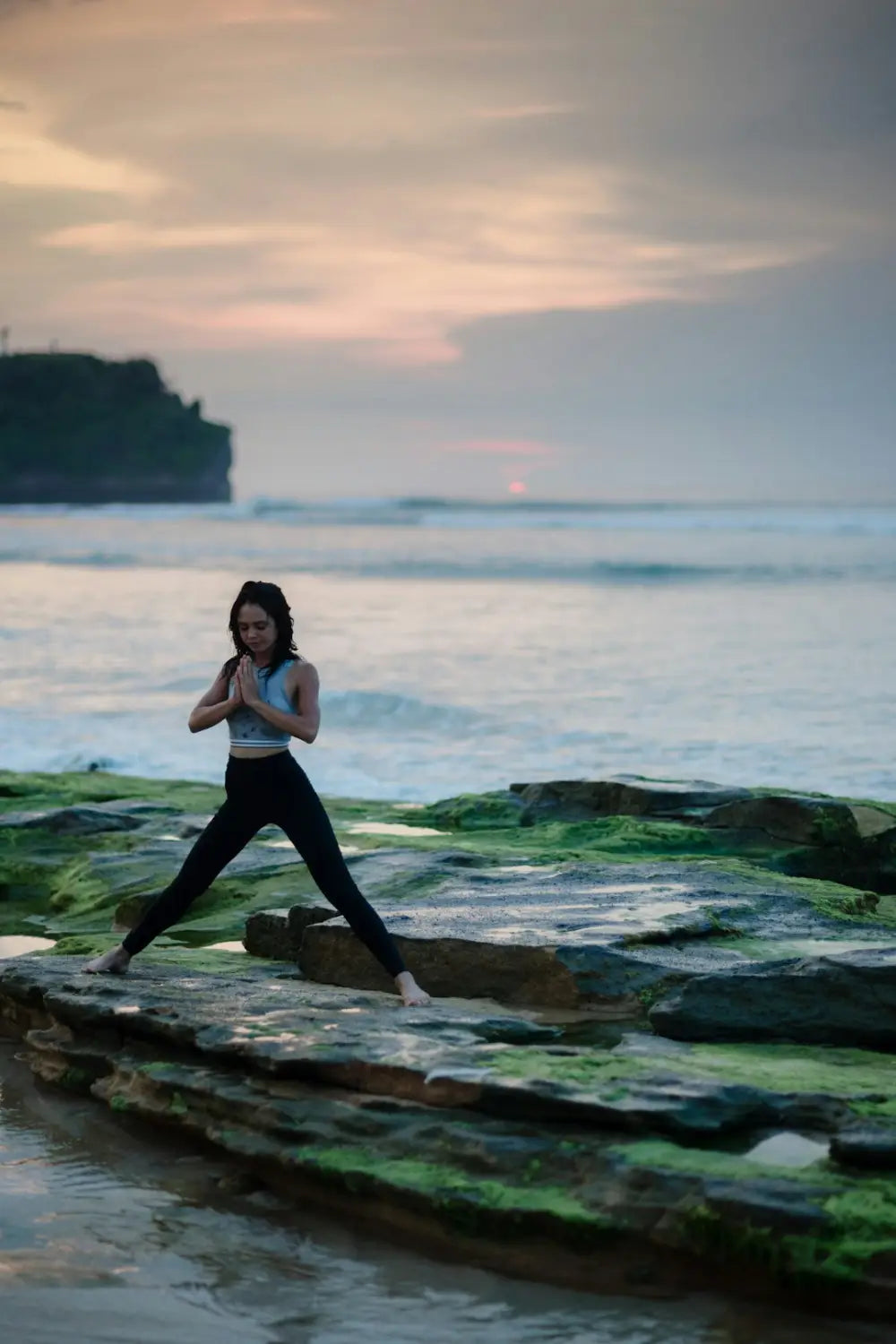 Woman in athletic wear practicing mindfulness on rocky Beach for stress management techniques
