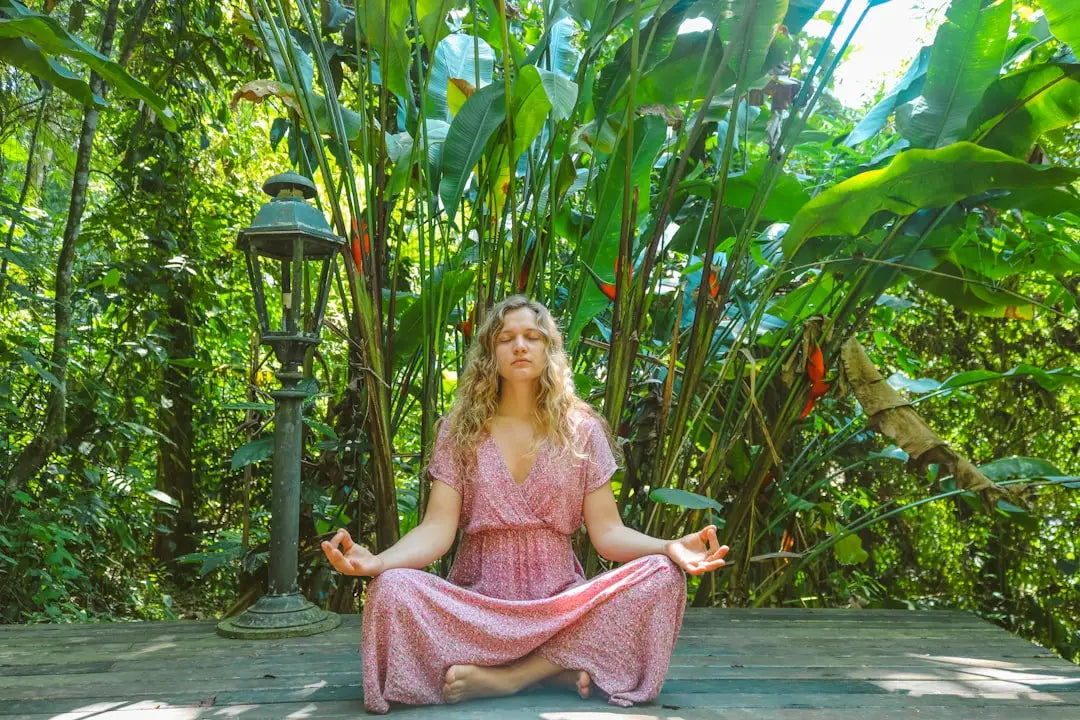 Woman meditating in a long pink floral dress practicing mindfulness for stress management
