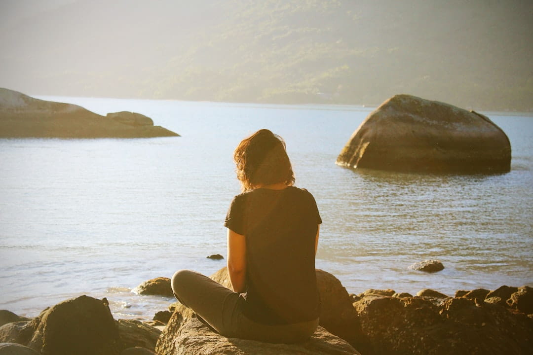Woman practicing mindfulness by water for stress management techniques and stress relief tips